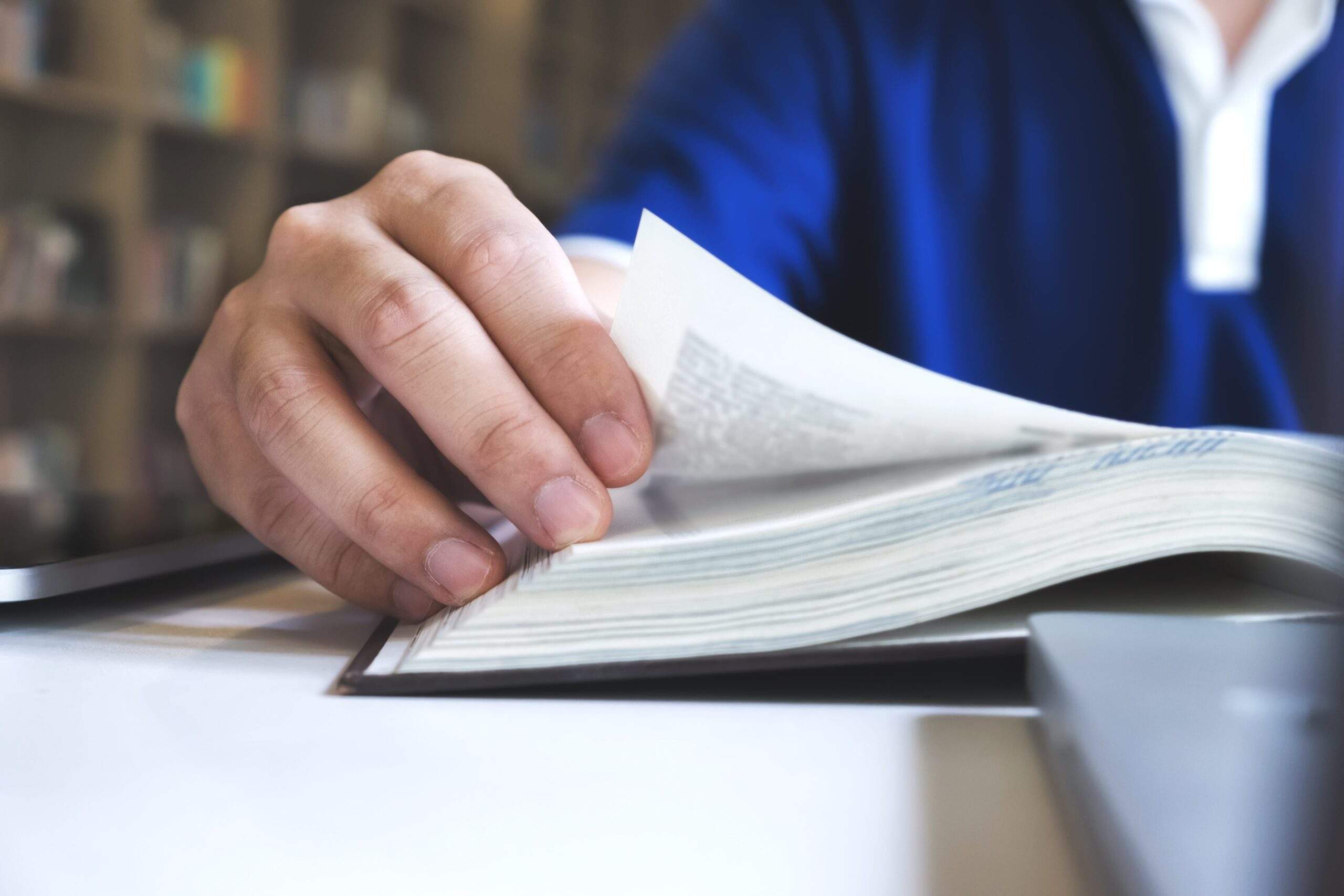 Close-up of a person flipping through a thick book, representing research and preparation for transfer pricing documentation requirements.